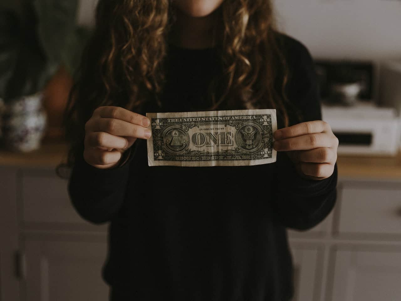 girl holding a dollar bill showing introverts make less money