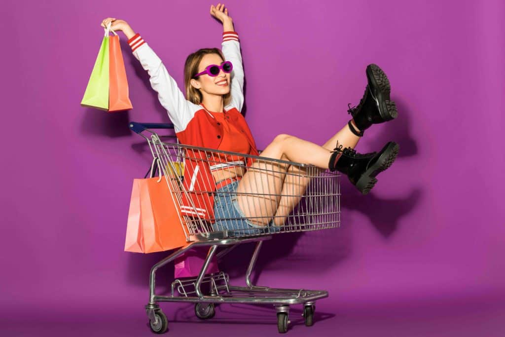 woman sitting in shopping cart with shopping bags