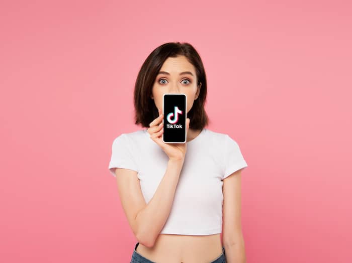 young woman holding smartphone with TikTok